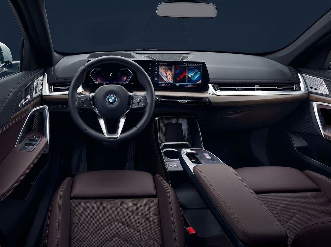 BMW X1 dashboard and front seats seen from the driver's door, steering wheel and twin screens